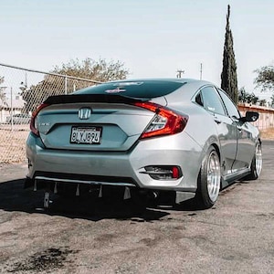 May include: A silver Honda Civic saloon with a black rear spoiler and a black rear diffuser. The car has tinted windows and a number plate that reads "8LYJ894".