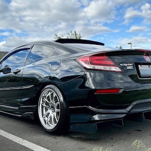 May include: A black Honda Civic Coupe with a rear spoiler and aftermarket wheels. The car has a black rear diffuser with a four-fin design. The car has a red Honda emblem on the back.