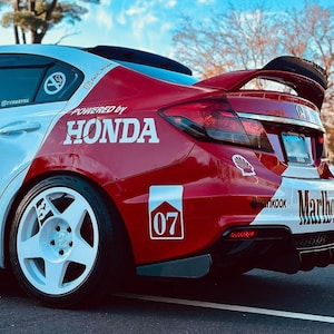 May include: A white and red Honda Civic with a black rear spoiler and white wheels. The car has a "Powered by Honda" sticker on the side and a "Marlboro" sticker on the back. The car also has a number "07" sticker on the side.