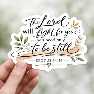 May include: A white sticker with black script that reads "The Lord will fight for you; you need only to be still - Exodus 14:14." The sticker has a watercolor-style background and is decorated with green and gold leaf accents.