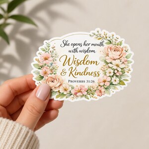 May include: A floral sticker with the text "She opens her mouth with wisdom, Wisdom & Kindness, Proverbs 31:26." The sticker features a white border and is decorated with watercolor-style pink and white flowers and green leaves.