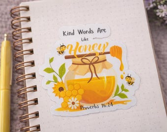 May include: A sticker with a honey theme, featuring a jar of honey, a honey dipper, and two bees. The text "Kind Words Are Like Honey" and "Proverbs 16:24" are also included. The sticker is on a dotted notebook.