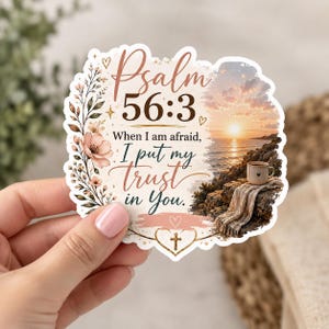 May include: A die-cut sticker featuring the text Psalm 56:3, When I am afraid, I put my trust in You. The design includes floral illustrations, a sunset ocean scene with a coffee mug on a blanket, and a small gold cross inside a heart.