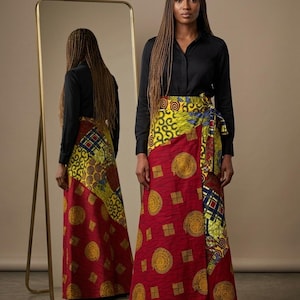 Può includere: Gonna lunga a portafoglio con un vivace design a fantasia rossa, gialla e blu. La gonna presenta uno stile avvolgente con chiusura a fiocco. La modella indossa una camicia nera a maniche lunghe. La gonna ha un motivo geometrico e circolare.