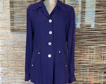 May include: A long-sleeved, purple button-up shirt with a collar and pockets. The shirt has white buttons and gold accents on the pockets.