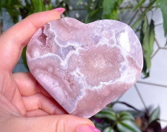 May include: A heart-shaped pink and white crystal with a swirling pattern. The crystal is smooth and polished.