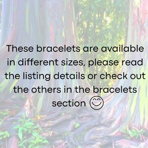 May include: Text on a blurred background of a tree trunk reads: "These bracelets are available in different sizes, please read the listing details or check out the others in the bracelets section". A smiley face emoji is at the end of the text.