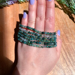 May include: A stack of green agate beaded bracelets. The bracelets are made of small, round beads and are stacked on top of each other.