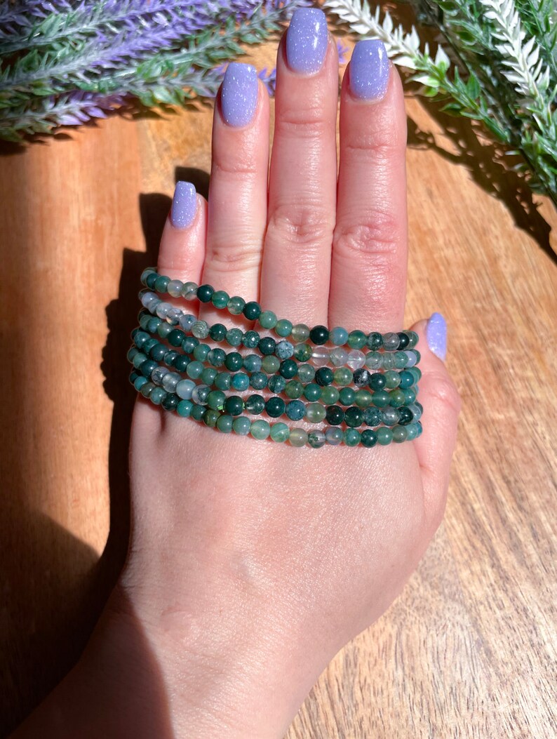 May include: A stack of green agate beaded bracelets. The bracelets are made of small, round beads and are stacked on top of each other.