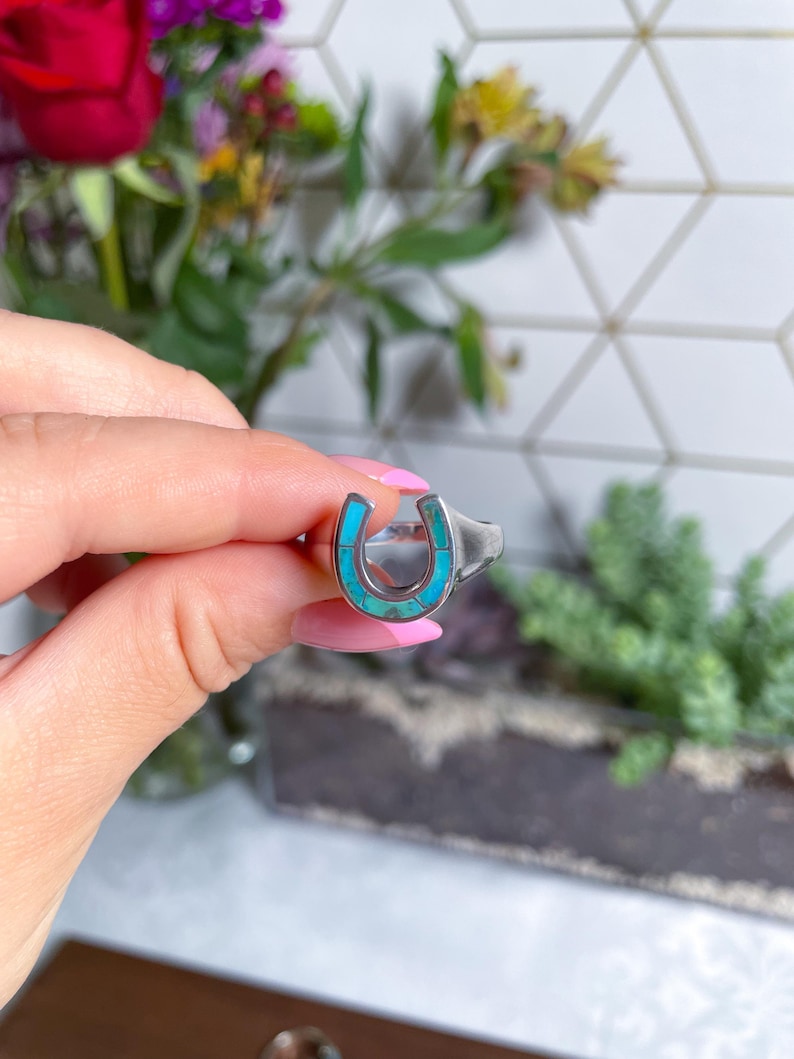 May include: A silver ring with a turquoise horseshoe design.