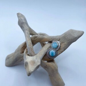 May include: A pair of silver earrings with blue opal stones set in a decorative silver bezel.