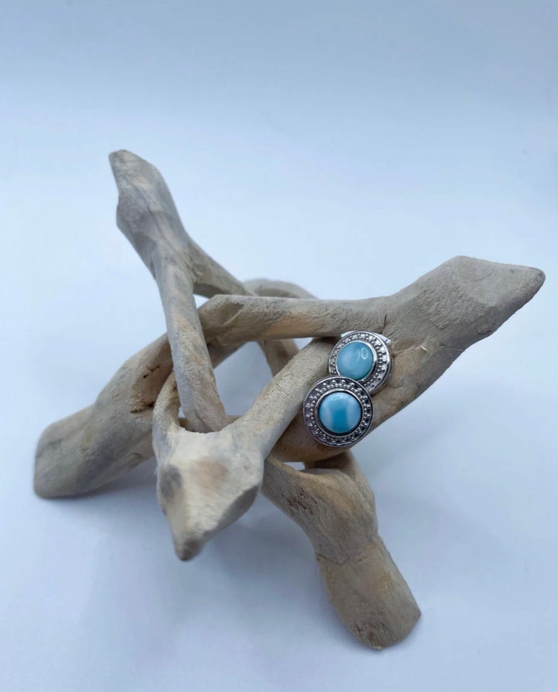 May include: A pair of silver earrings with blue opal stones set in a decorative silver bezel.