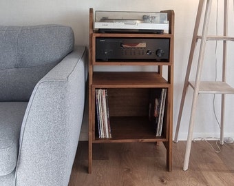 May include: A wooden record player stand with three shelves. The top shelf has a turntable, the middle shelf has a stereo receiver, and the bottom shelf has vinyl records.