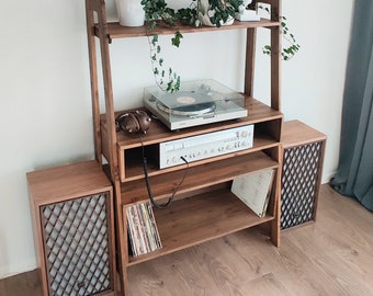 May include: A wooden record player stand with two speakers, a turntable, and a receiver. The stand has two shelves for storing records and other items. There are plants on the top shelf.