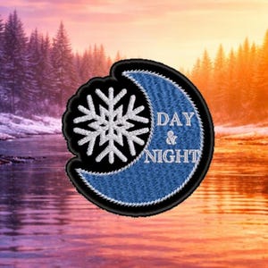 May include: Embroidered patch featuring a white snowflake and a blue crescent moon with the words "DAY & NIGHT". The patch has a black border and is set against a scenic background of a river and trees.