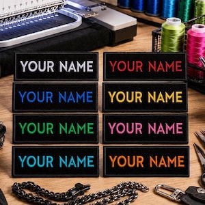 Puede incluir: Parches bordados con el texto "YOUR NAME" en blanco, rojo, azul, amarillo, verde, rosa y naranja sobre fondo negro. Se exhiben sobre una superficie de madera, junto con suministros de costura.