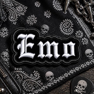 May include: A black and white embroidered patch with the word "Emo" in gothic lettering. The patch is on a black bandana with skull and paisley patterns. A silver chain and guitar pick with a skull are also visible.