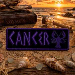 May include: A black rectangular patch embroidered with the word "CANCER" in purple, along with a purple crab symbol. The patch is surrounded by seashells, a compass, a lantern, and a bottle with a scroll, all set against a beach sunset.