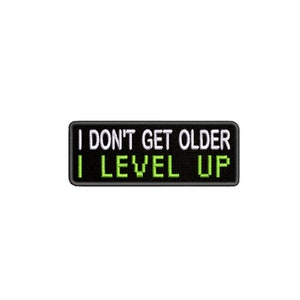 May include: Black embroidered patch with white text that reads "I don't get older I level up" in a pixelated font.
