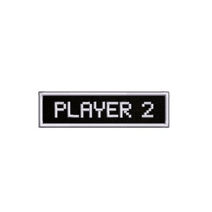Könnte beinhalten: Ein schwarzer rechteckiger Patch mit weißem Rand und dem Text "PLAYER 2" in weißen Pixelbuchstaben.