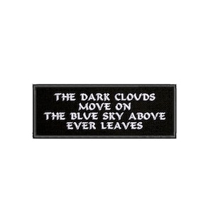 Puede incluir: Parche bordado negro con texto blanco que dice "The dark clouds move on the blue sky above ever leaves."