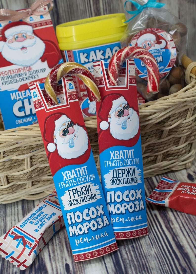 Puede incluir: Dos bastones de caramelo rojo y blanco con envoltorios azules y blancos. Los envoltorios presentan a un Pap&aacute; Noel de dibujos animados con gafas de sol y el texto "Хватит грызть сосули! Грызи эксклюзив! Посох Мороза реплика".