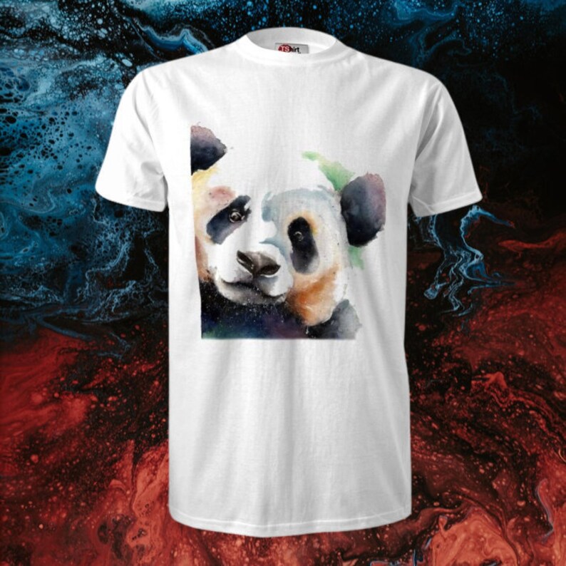 Op de afbeelding: Een wit T-shirt met een aquarel schilderij van een pandabeer gezicht. De panda kijkt naar links en heeft zwarte ogen en een zwarte neus. De achtergrond van het schilderij is een mix van blauw, groen en paars.