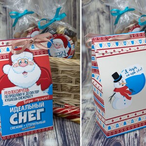 Puede incluir: Dos bolsas de regalo festivas con tem&aacute;tica invernal. Una bolsa presenta a un Pap&aacute; Noel de dibujos animados con el texto "Nieve ideal" y la otra presenta a un mu&ntilde;eco de nieve de dibujos animados con el texto "Estoy aqu&iacute; por la nieve".