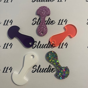 Peut inclure: Quatre porte-clés différents avec un logo Studio 114. Les porte-clés sont en acrylique et présentent différentes couleurs et finitions pailletées. Les porte-clés ont la forme d'une petite figurine stylisée.