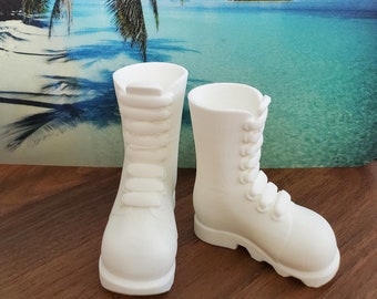 Könnte beinhalten: Zwei weiße Keramik-Stiefel mit Schnürsenkeln. Die Stiefel stehen auf einer Holzoberfläche.