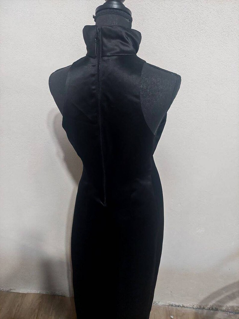 Puede incluir: Un vestido negro sin mangas con cuello alto y una cremallera en la espalda.