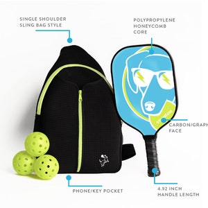 May include: A black and green single-shoulder sling bag with a zippered pocket and a small dog logo. The bag is next to a blue and green pickleball paddle with a dog graphic and the text "syuton". Three green pickleballs are in front of the bag. The paddle has a 4.92 inch handle length.