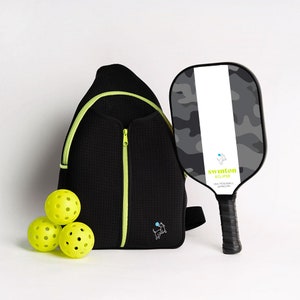 May include: A black and neon green pickleball bag with a black and gray camo pickleball paddle with the text "swinton eclipse USA PICKLEBALL APPROVED" and three yellow pickleballs.