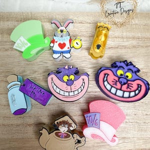 May include: A set of eight 3D printed Alice in Wonderland themed figurines. The figurines include the Mad Hatter, the Cheshire Cat, the White Rabbit, the Queen of Hearts, the Drink Me bottle, the Eat Me cookie, and two versions of the Mad Hatter's hat.