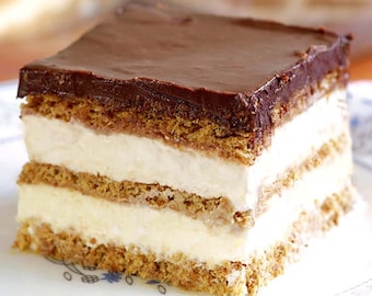 May include: A close-up of a layered dessert with a chocolate topping. The dessert is made with graham cracker crust, vanilla pudding, and whipped cream.