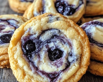 Può includere: Primo piano di diversi biscotti a spirale ai mirtilli. I biscotti hanno un esterno marrone dorato, leggermente strutturato e un ripieno a spirale bianco e viola cremoso. I mirtilli freschi sono visibili al centro di ogni biscotto, creando una delizia visivamente accattivante.
