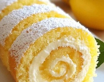以下が含まれることがあります： 白いクリームと粉砂糖をかけた黄色のレモンロールケーキ。ケーキはカットされて、中のクリームが見えるようになっている。