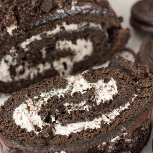 May include: A chocolate cake roll with a chocolate frosting and a white cream filling. The cake is covered in crushed Oreo cookies.