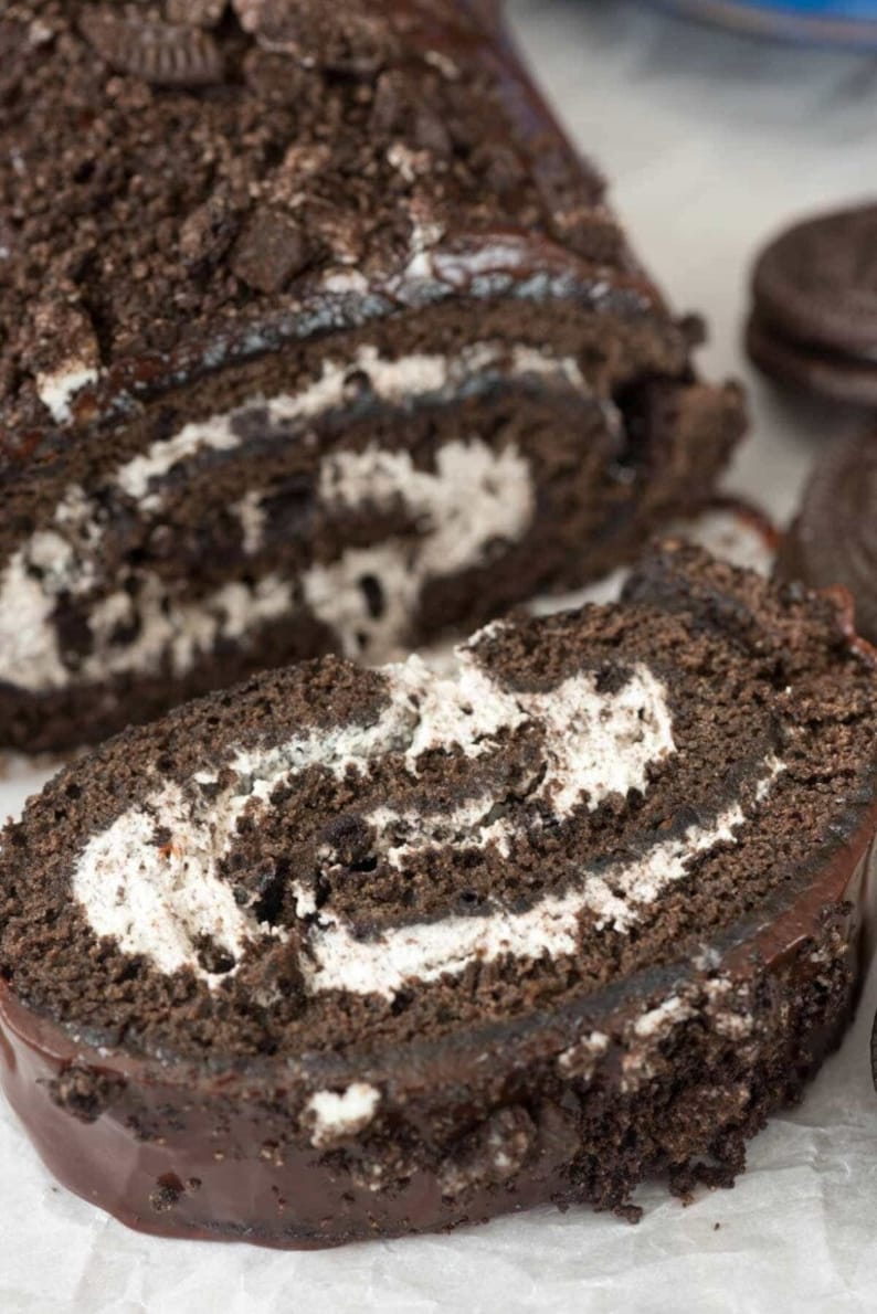 May include: A chocolate cake roll with a chocolate frosting and a white cream filling. The cake is covered in crushed Oreo cookies.