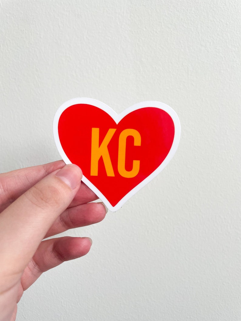 May include: Red heart-shaped sticker with a white outline and the text "KC" in yellow.