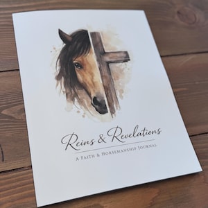 May include: A white journal with the title "Reins & Revelations" and the subtitle "A Faith & Horsemanship Journal." The cover features a watercolor illustration of a horse's head and a cross.