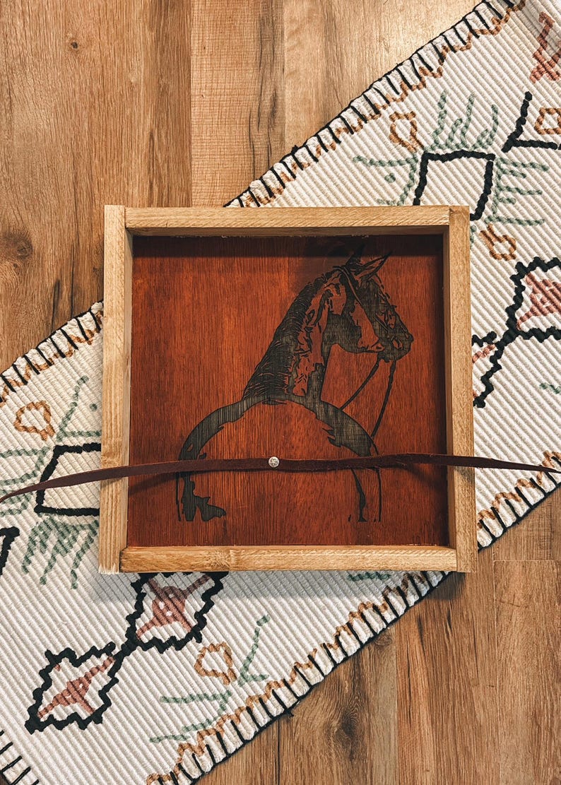 May include: A wooden tray with a dark brown stain features a laser-etched silhouette of a horse's head and neck. The tray has a leather strap across the top.