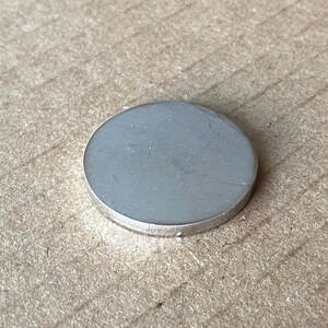 May include: A silver-coloured metal disc with a smooth surface.