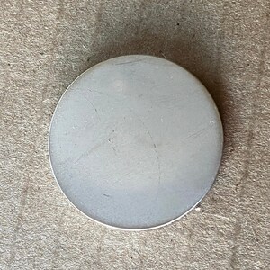 May include: A plain white round ceramic coaster with a smooth surface.