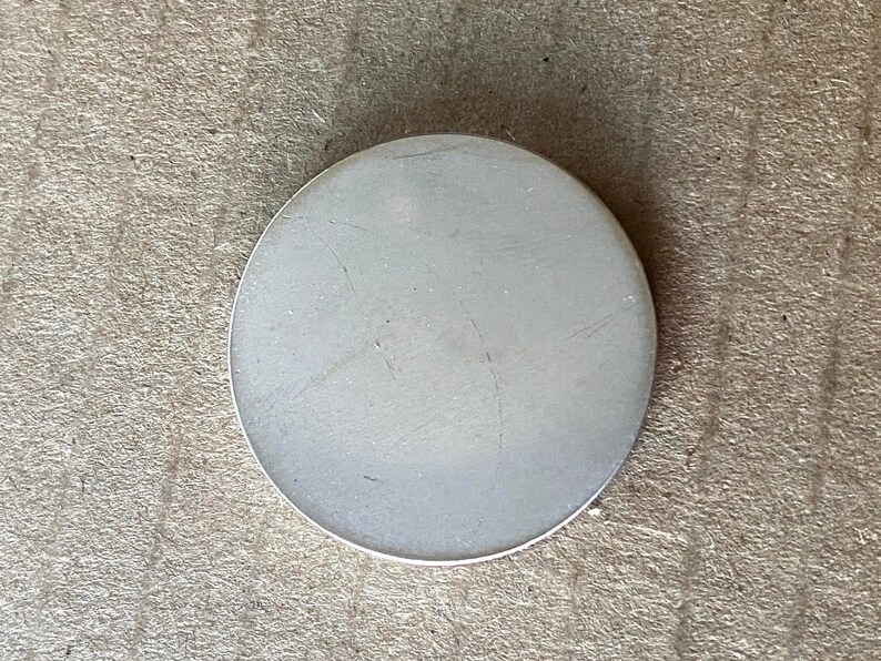 May include: A plain white round ceramic coaster with a smooth surface.