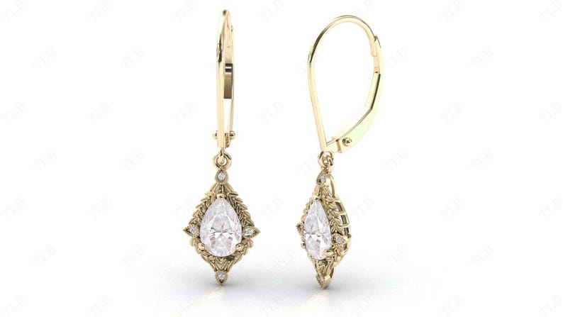 Puede incluir: Un par de pendientes de oro con una piedra preciosa transparente en forma de pera rodeada de piedras preciosas transparentes m&aacute;s peque&ntilde;as y un dise&ntilde;o en forma de hoja.