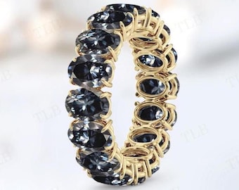 May include: A gold band ring with a row of oval-shaped dark blue gemstones.