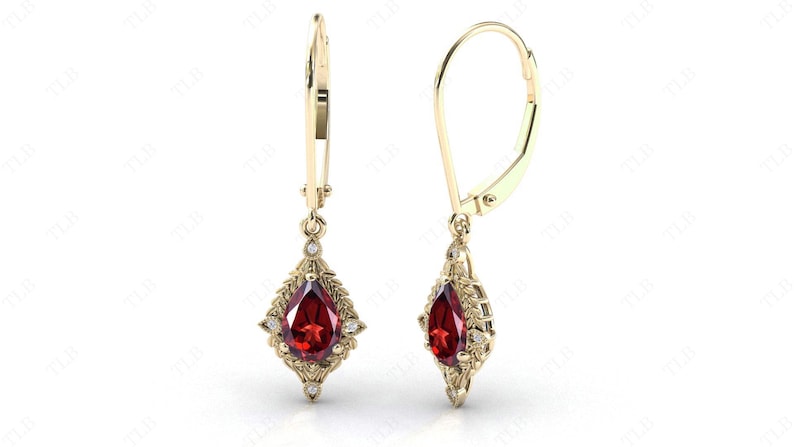 May include: A pair of gold dangle earrings with a pear-shaped red gemstone and smaller clear gemstones set in a delicate floral design.