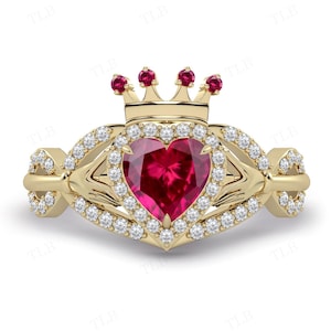 Peut inclure: Une bague en or avec un rubis en forme de cœur entouré d'un halo de petits diamants. La bague présente un motif de nœud celtique et une couronne sur le dessus.