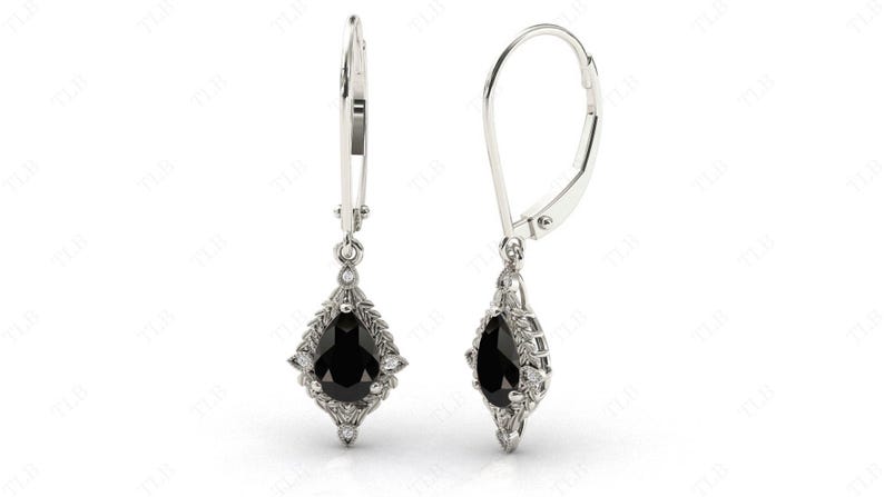 May include: A pair of silver dangle earrings with a pear-shaped black gemstone surrounded by smaller white gemstones. The earrings have a leverback closure.
